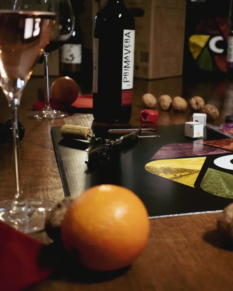 Calice di vino sulla tavola di casa, accanto a una bottiglia Primavera, noci e arance